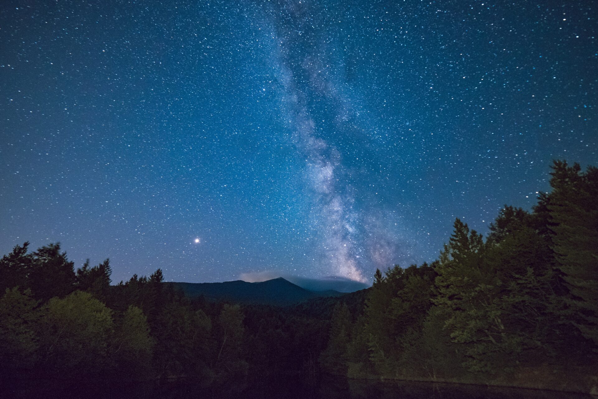 A night sky with the milky way in the distance.