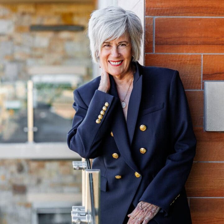 Smiling woman in a navy suit outdoors.
